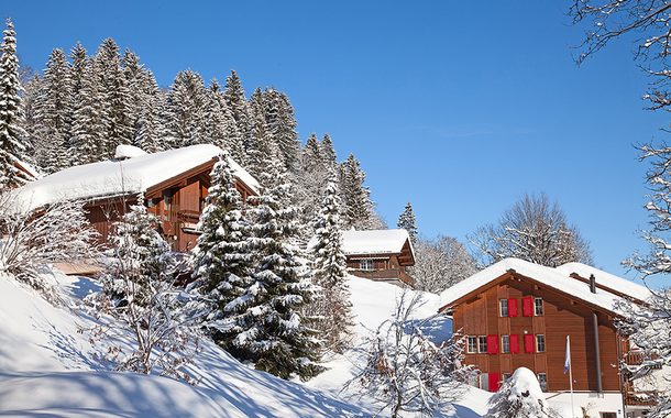 Schnee in den Bergen mit Holzhäuser und Bäumen